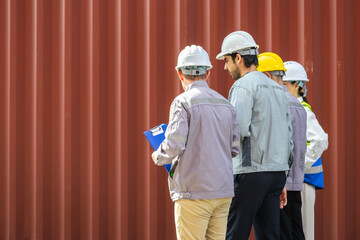 Diverse industrial team of engineers and foremen inspecting a shipping container at the port, Group of workers with hardhats discussing logistics near cargo containers