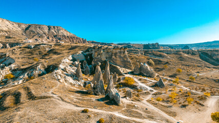 Cappadocia, Goreme, is revealed from a drone view showing fairy chimneys, carved valleys, ancient cave dwellings, and layered volcanic rock formations shaping the landscape from above.