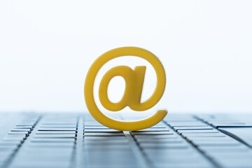 Yellow at symbol standing on a computer keyboard. Email, internet contact, online identity, and digital messaging concept.