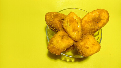 Breaded fried bananas on a plate bowl on a yellow background.