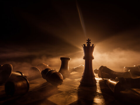 Chess king standing upright among fallen pieces on a board, representing strategy, victory, and leadership.