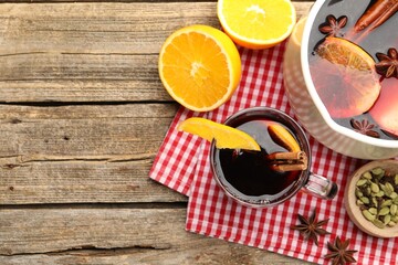 Mug with tasty mulled wine and ingredients on wooden table, flat lay. Space for text