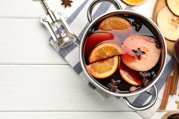 Tasty mulled wine in pot, ingredients and corkscrew on white wooden table, flat lay. Space for text