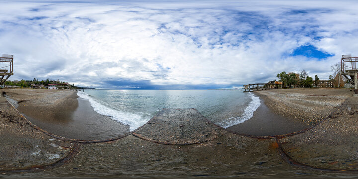 A seamless spherical HDRI panorama, a 360-degree view of a sandy beach by the sea on a cloudy summer day with beautiful clouds in equirectangular projection, VR content. Panorama of an old sea pier.