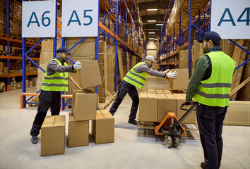 Warehouse workers move boxes on pallet trolley. Tall shelving and aisles show efficient logistics...