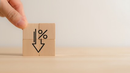 A hand delicately arranges wooden blocks, revealing a decrease percentage symbol. A visual metaphor for falling financial indicators, highlighting economic adjustments and shifts.