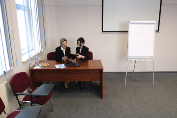 Two businesswomen at a desk in an office analyzing documents, business meeting, cooperation and project discussion