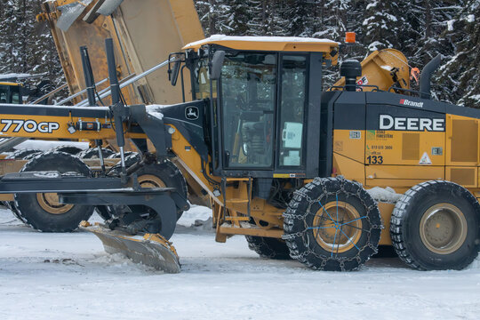 Canada, Quebec, 05 December 2025 : Snow covers large yellow grader working at snowy forest construction site
