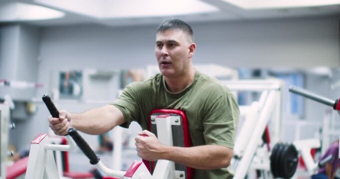 Middle aged Caucasian man working out in the gym. A focused Caucasian man works his back muscles intensely using the hammer machine, maintaining strong form throughout his gym session.