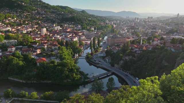 Scenic beauty of Sarajevo with aerial views of the Miljacka River and vibrant city life during sunset. Flying over summer Sarajevo, Bosnia and Herzegovina