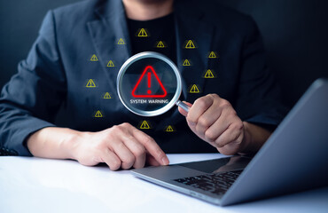 System warning hacked alert, cyber attack on computer network. Businessman using laptop with magnifying glass detects security risks, symbolizing malware, data breach and cybersecurity threat.