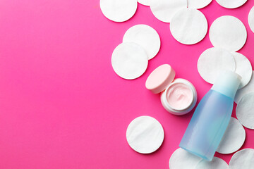Fototapeta premium Clean cotton pads and cosmetic products on pink background, flat lay. Space for text
