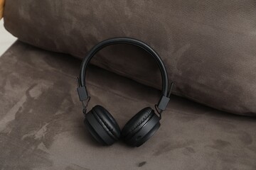 Pair of stylish headphones on gray sofa, closeup
