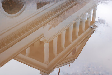 Fototapeta premium Architectural symmetry and historic features reflected on rainwater in urban setting