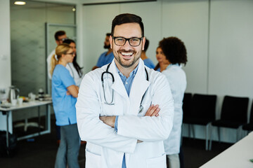 Portrait of a young confident and friendly doctor in fron of group of doctors and nurses. Teamwork and healthcare concept