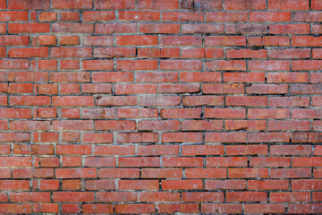 This is a close-up image of an old, weathered brick wall with varying reddish-brown tones. The rough texture and imperfect mortar between the horizontal rows of bricks fill the entire frame.