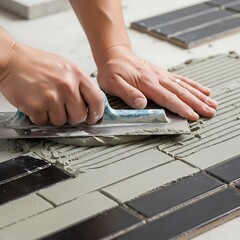 Close-up view of tiler's hands applying mortar to tiles in staggered pattern