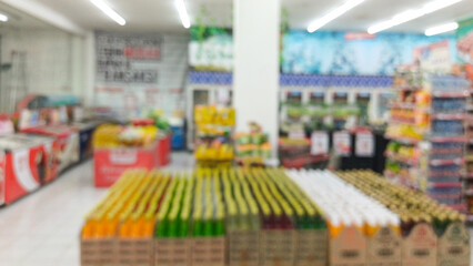 Defocused blur, bokeh background of a supermarket grocery store aisle with brightly colored bottled beverages and product racks. Concept for retail shopping, consumerism, and food business backdrop.