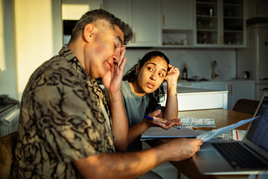 Adult couple stressed paying bills at home kitchen