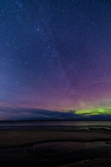 Milky Way galaxy and aurora borealis over Baltic Sea coast in Latvia