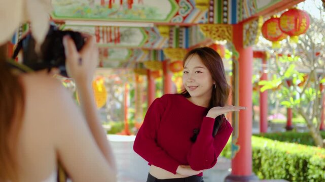 Two joyful young asian woman embrace their playful spirits as they take stunning snapshots at a beautiful Chinese temple, filled with colors and cultural richness under the sun.