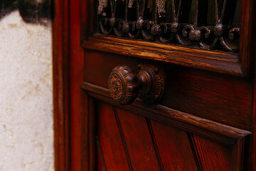 Vintage wooden door with ornate knob and iron grate design