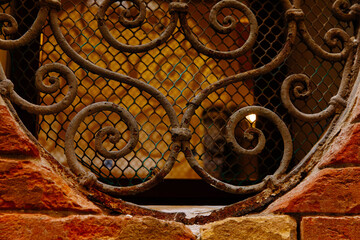 Fototapeta premium Intricate wrought iron grille on vintage brick wall with warm lighting