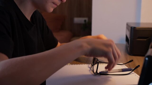 Teenage boy at desk late at night, rubbing tired eyes and look frustrated and overwhelmed while struggling with homework and exam prep under pressure and fatigue