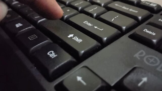 Close-up of Hand Pressing Enter and Shift Keys on a Black Keyboard