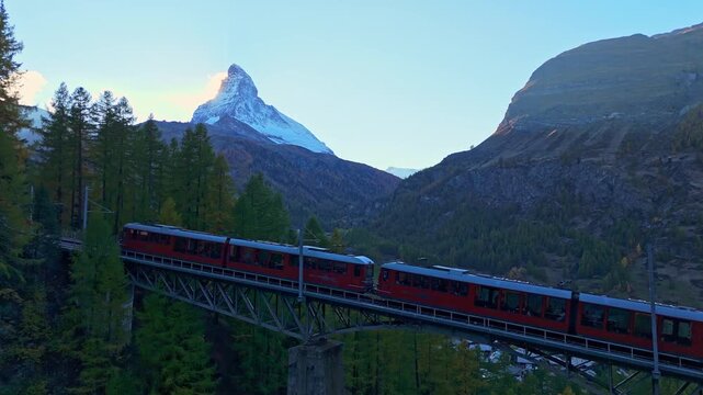 Rack Railway Red Train on Findelbachbrucke Bridge, Matterhorn Mountain and Larches in Autumn Evening. Swiss Alps. Aerial Drone Shot. Zermatt, Valais, Switzerland