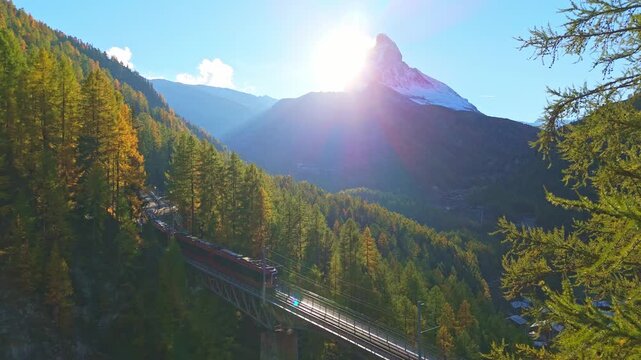 Rack Railway Red Train on Findelbachbrucke Bridge, Matterhorn Mountain and Larches in Autumn Evening. Swiss Alps. Aerial View. Zermatt, Valais, Switzerland