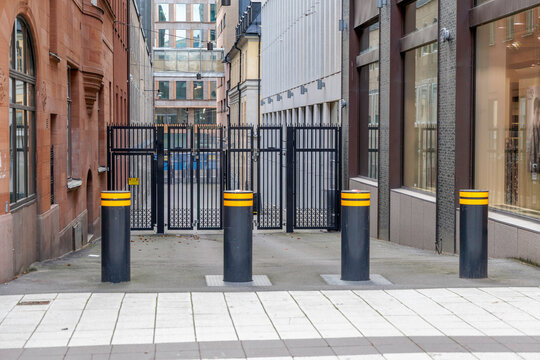 Row of Black and Yellow Security Bollards in Front of a Metal Gate