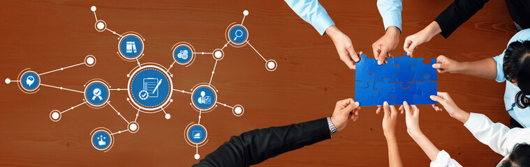 A diverse team collaborates over a puzzle piece, surrounded by icons representing business and technology, highlighting creativity and connection in a professional setting. Amity