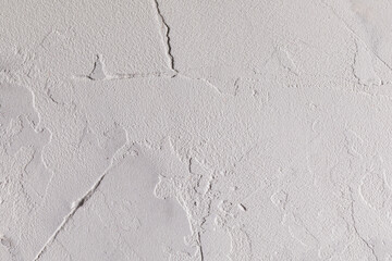 A white-gray, irregularly plastered wall, with clearly visible plaster strokes. Horizontal photo