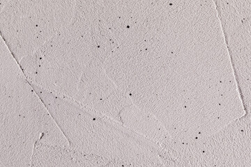 A gray, haphazardly plastered wall is splattered with black paint. Horizontal photo
