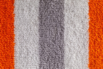 Fototapeta premium A close-up shot of a textured gray towel, with orange and white strips showcasing its fluffy and soft fabric loops.