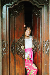 Balinese Woman Between Traditional Carved Wooden Doors