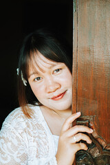 Balinese Woman Peeking from Behind Carved Traditional Wooden Door