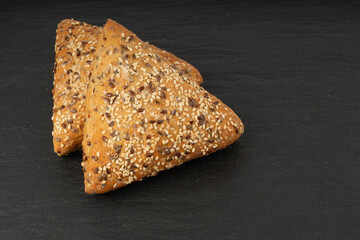 Triangular bun closeup. Wheat bread with sesame and flax seeds, healthy whole grain bakery