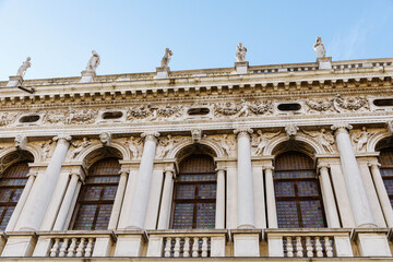 Obraz premium Venice, Italy - December 05, 2025: Architectural details of historic building facade with ornate columns and sculptures against a clear blue sky, showcasing Renaissance artistry and craftsmanship