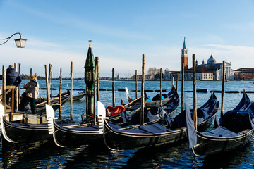 Venice, Italy - December 05, 2025: Gondolas lined up in the serene waters of Venice, showcasing iconic architecture and vibrant reflections, perfect for travel enthusiasts and photographers