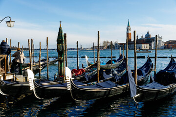 Venice, Italy - December 05, 2025: Gondolas lined up at a picturesque dock in Venice, showcasing the serene waters and historic architecture of the iconic city