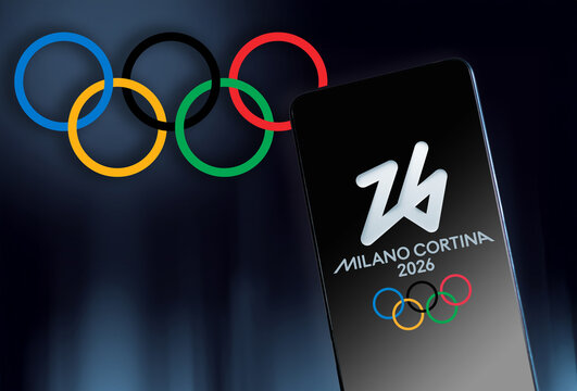 MILAN, ITALY, DECEMBER 12, 2025. A smartphone screen displays the Milano Cortina 2026 emblem while the iconic Olympic rings float in the dark blue background, the future of mobile sports streaming