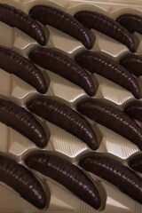 Close-up of assorted chocolate-covered candies arranged in a box. Focus on glossy dark chocolate