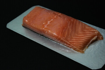 Close-up of fresh raw salmon fillet on a cutting surface. Visible texture, natural fat lines, and moist surface