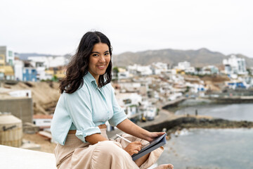 Fototapeta premium Young woman creating digital art with tablet by sea
