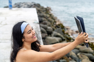Young woman taking selfie with tablet by sea
