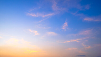 Obraz premium Beautiful sunset sky with soft pastel clouds. Golden hour light fading into deep blue, creating a dreamy ethereal atmosphere. Perfect for serene backgrounds and nature concepts