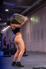 A woman is carrying a large bag on her back while in a gym setting