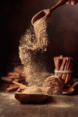 Cinnamon powder is poured into a wooden bowl.